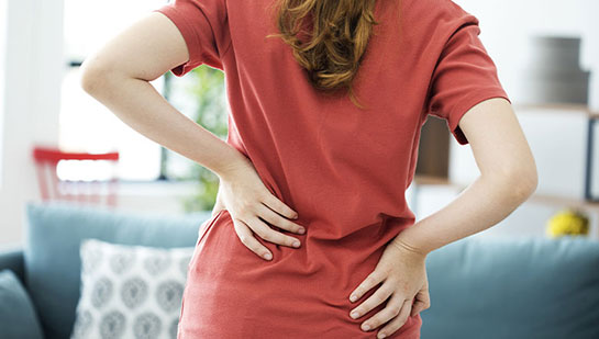 Woman holding lower back in pain before visiting Louisville chiropractor